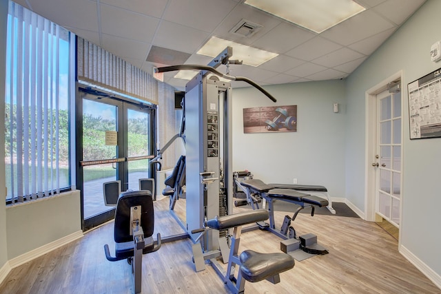 workout room with a paneled ceiling, wood-type flooring, and french doors