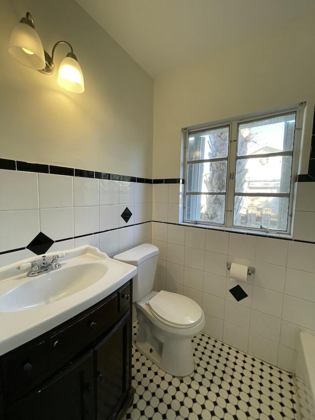 bathroom with tile walls, toilet, and vanity