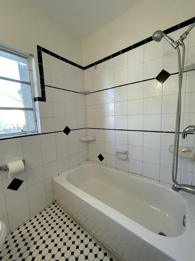 bathroom featuring tile walls, tiled shower / bath, and toilet