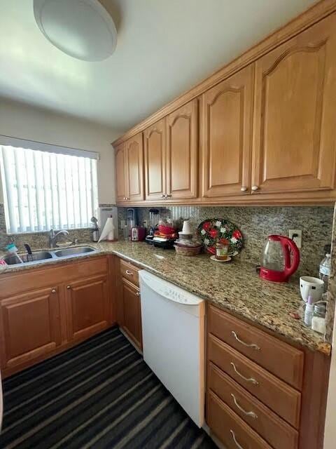 kitchen featuring dishwasher, decorative backsplash, light stone countertops, and sink