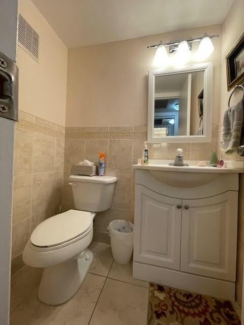 bathroom featuring vanity, tile walls, and toilet