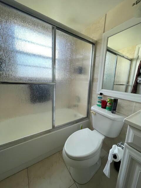 full bathroom with tile patterned floors, toilet, vanity, and combined bath / shower with glass door