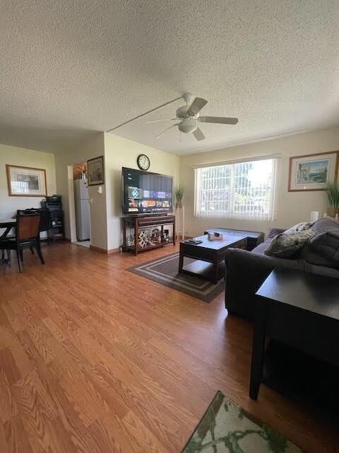 living room with a textured ceiling, hardwood / wood-style flooring, and ceiling fan