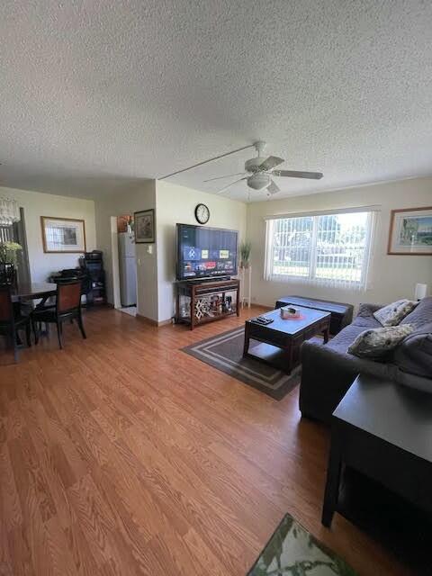 living room with hardwood / wood-style floors, a textured ceiling, and ceiling fan