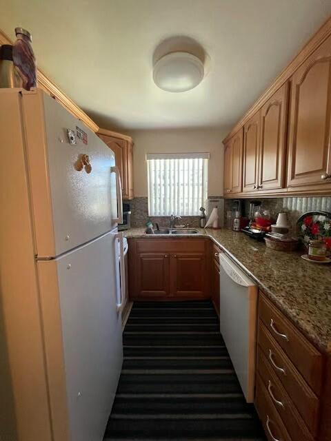 kitchen featuring dishwasher, white refrigerator, sink, tasteful backsplash, and light stone counters