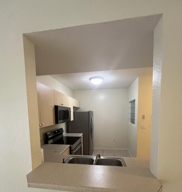 kitchen with kitchen peninsula, sink, light tile patterned flooring, and appliances with stainless steel finishes