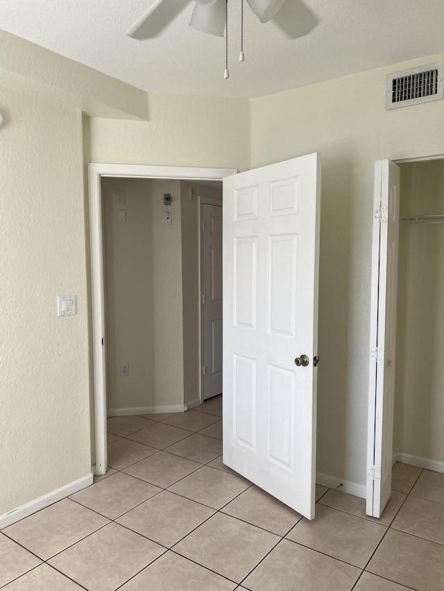 unfurnished bedroom featuring ceiling fan, a closet, and light tile patterned floors