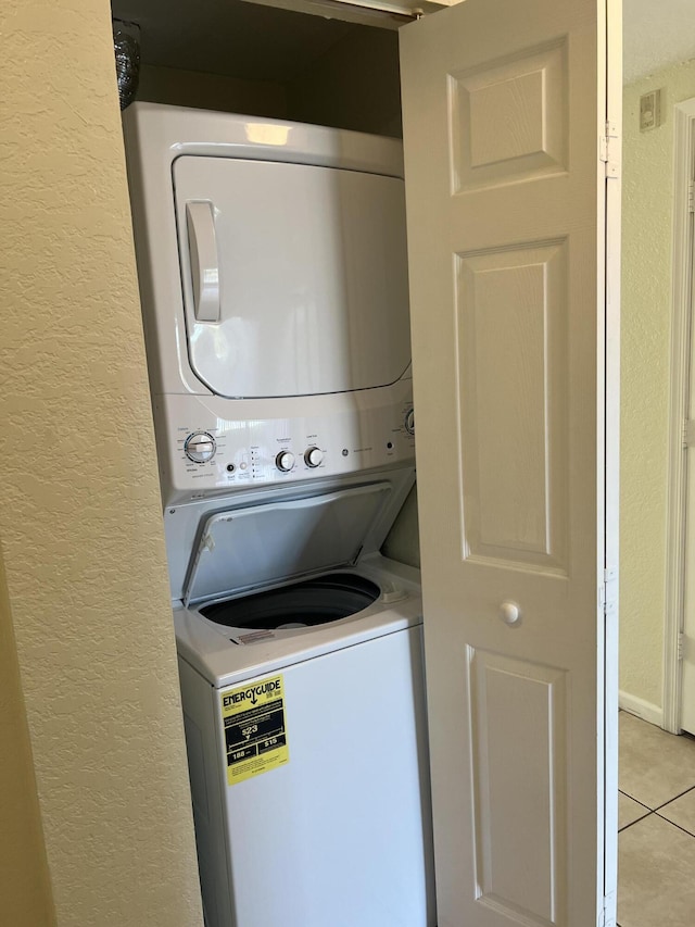 laundry room with stacked washer / drying machine and light tile patterned floors