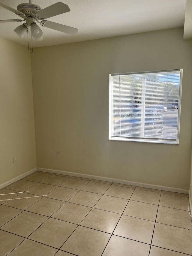 tiled spare room featuring ceiling fan