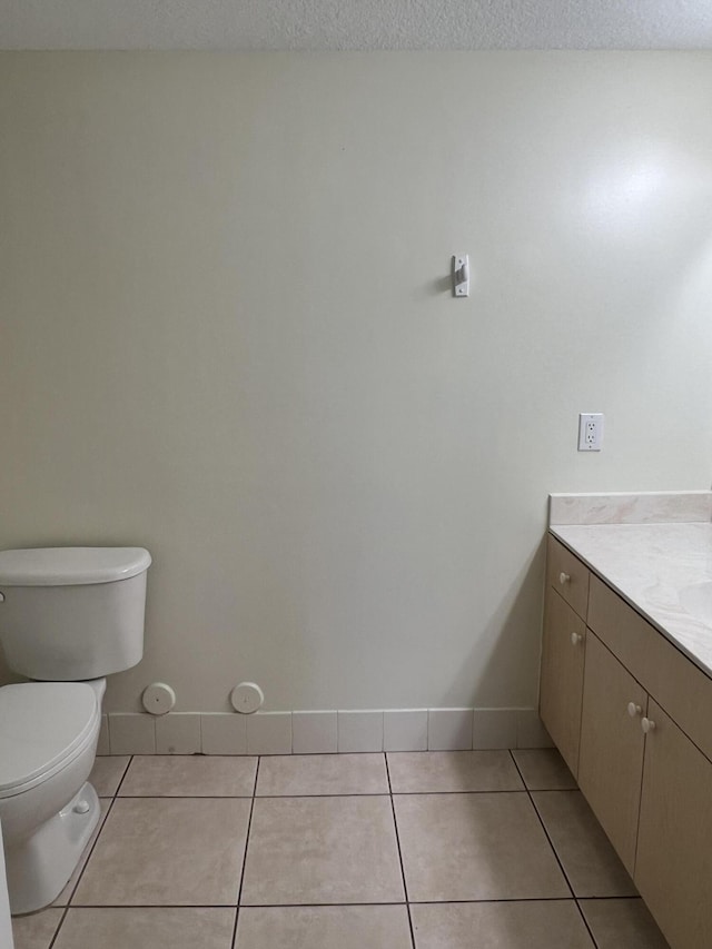 bathroom with tile patterned flooring, a textured ceiling, vanity, and toilet