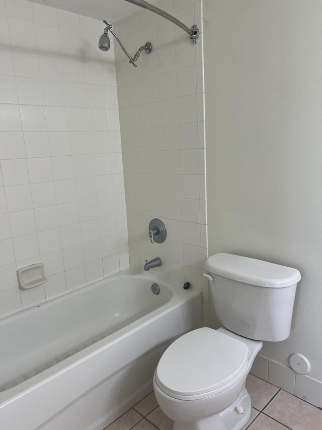 bathroom featuring tile patterned flooring, tiled shower / bath combo, and toilet