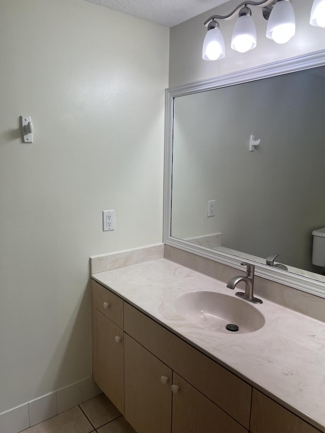 bathroom with tile patterned floors, vanity, a textured ceiling, and toilet