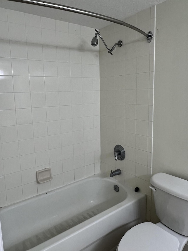 bathroom with tiled shower / bath combo and toilet