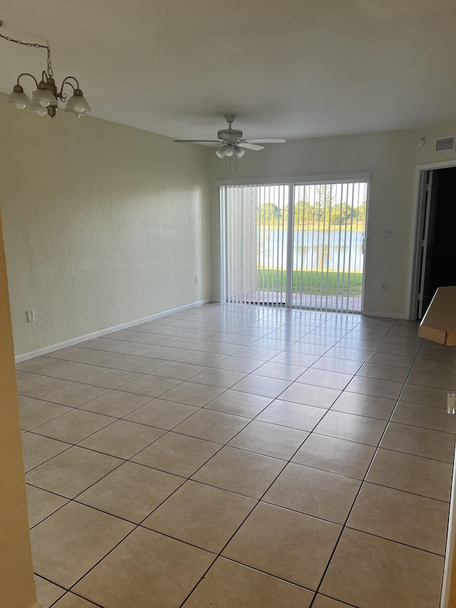 empty room with ceiling fan with notable chandelier and light tile patterned flooring