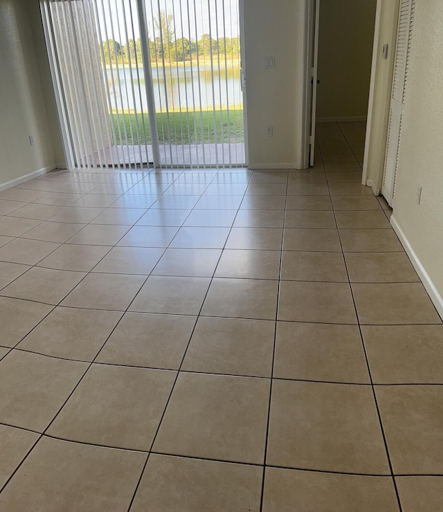 unfurnished room featuring a water view and light tile patterned floors