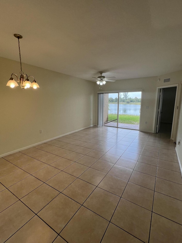 unfurnished room featuring ceiling fan with notable chandelier, a water view, and light tile patterned floors