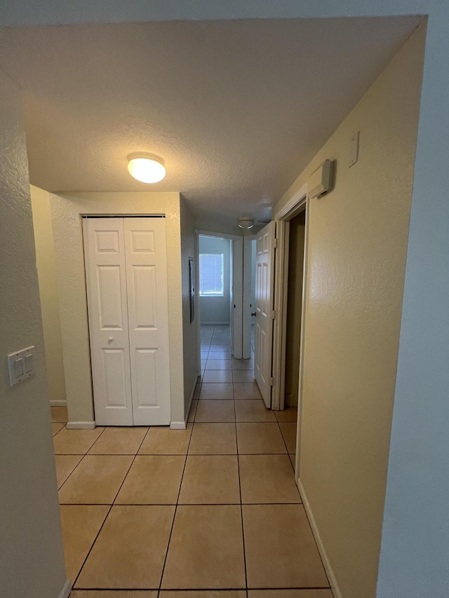 corridor with light tile patterned flooring and a textured ceiling