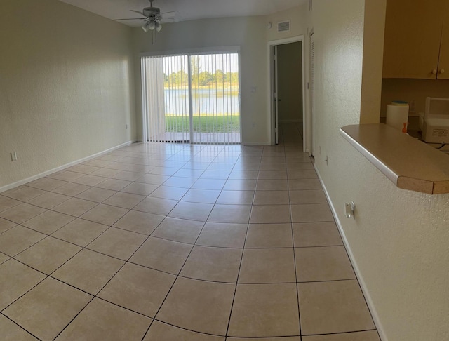 tiled spare room with ceiling fan and a water view