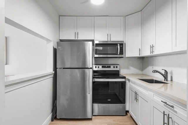 kitchen with stainless steel appliances, white cabinetry, light hardwood / wood-style floors, and sink