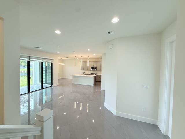 kitchen featuring backsplash, a center island with sink, sink, hanging light fixtures, and stainless steel appliances