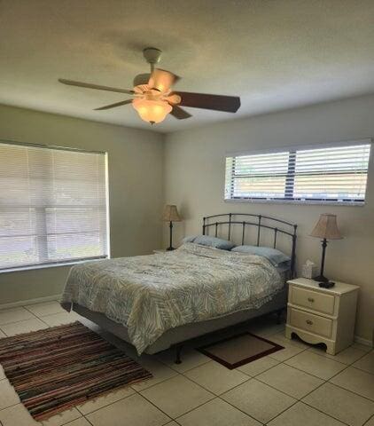 bedroom with multiple windows, ceiling fan, and light tile patterned floors