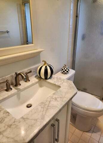 bathroom with tile patterned floors, vanity, toilet, and a shower with door