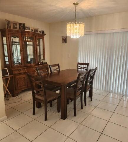 dining space with light tile patterned floors and an inviting chandelier