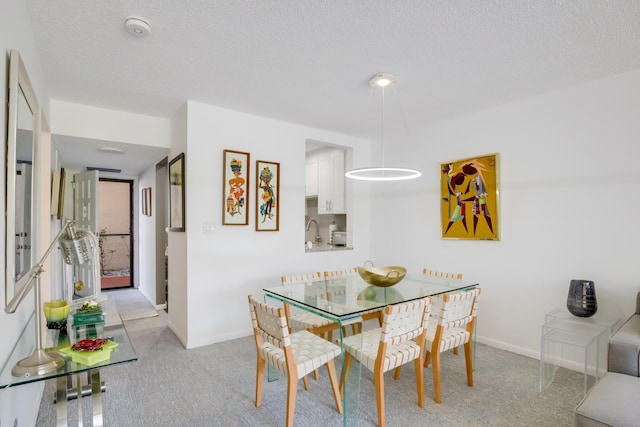 dining area featuring light colored carpet and a textured ceiling