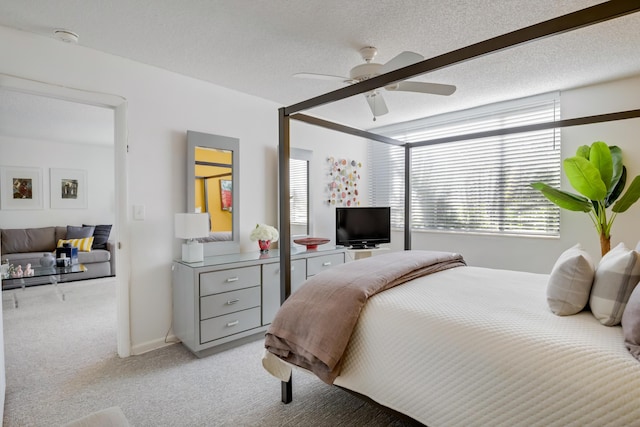 bedroom featuring multiple windows, ceiling fan, light carpet, and a textured ceiling