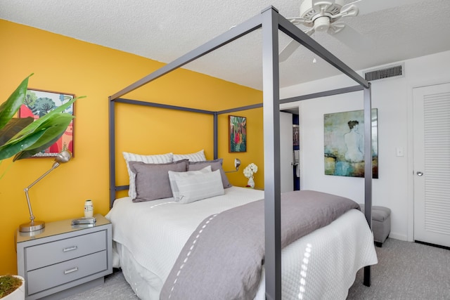 bedroom with ceiling fan, light carpet, and a textured ceiling