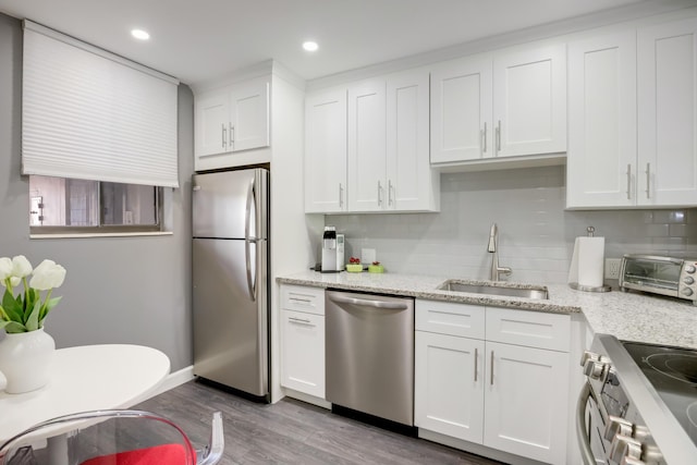 kitchen with stainless steel appliances, white cabinetry, light hardwood / wood-style floors, and sink