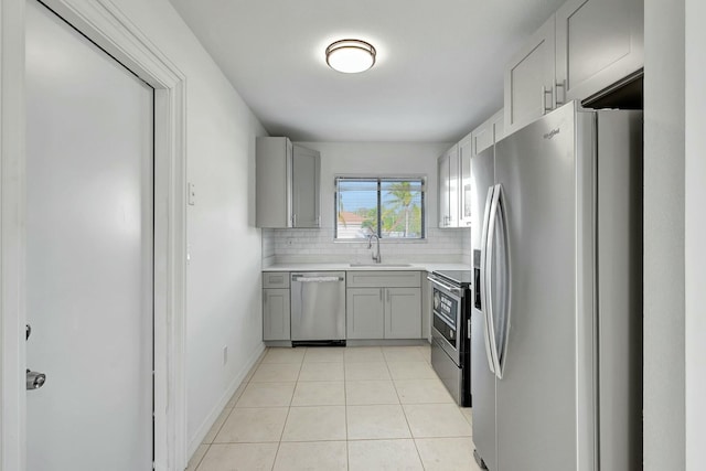 kitchen featuring decorative backsplash, gray cabinetry, stainless steel appliances, sink, and light tile patterned floors