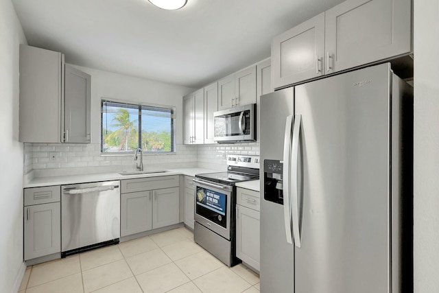 kitchen with gray cabinetry, decorative backsplash, sink, and stainless steel appliances