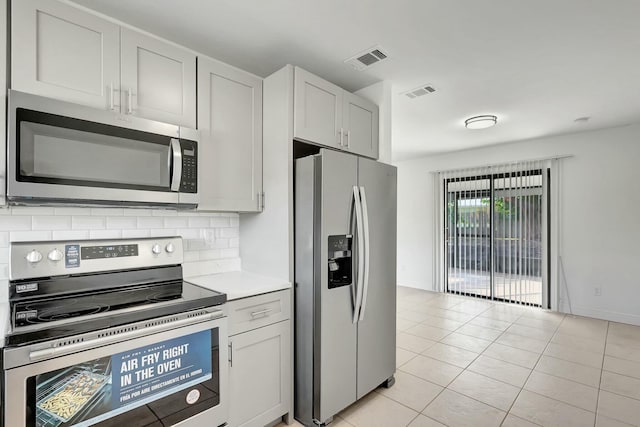 kitchen featuring decorative backsplash, light tile patterned flooring, and stainless steel appliances