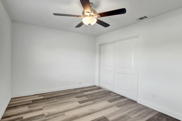 unfurnished bedroom featuring ceiling fan, light hardwood / wood-style flooring, and a closet