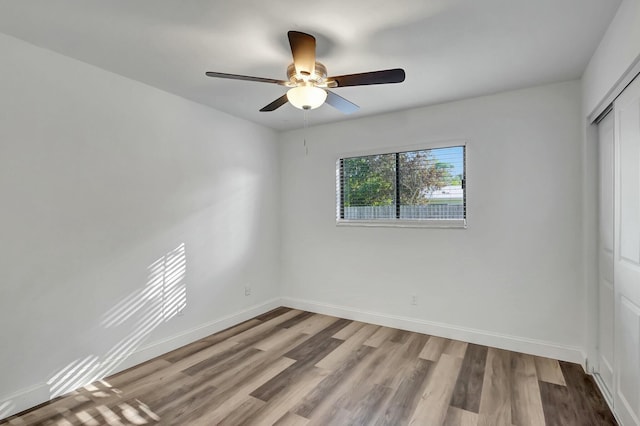 unfurnished bedroom with hardwood / wood-style flooring, ceiling fan, and a closet