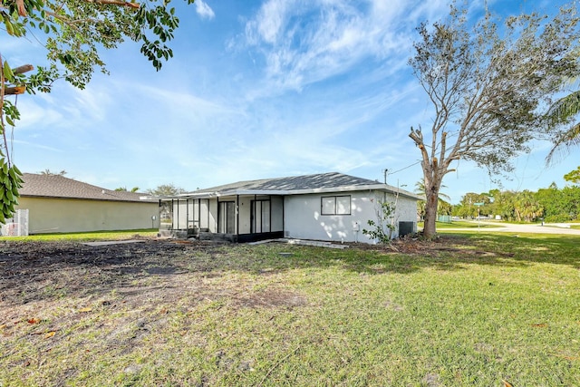 back of property with a sunroom, cooling unit, and a lawn