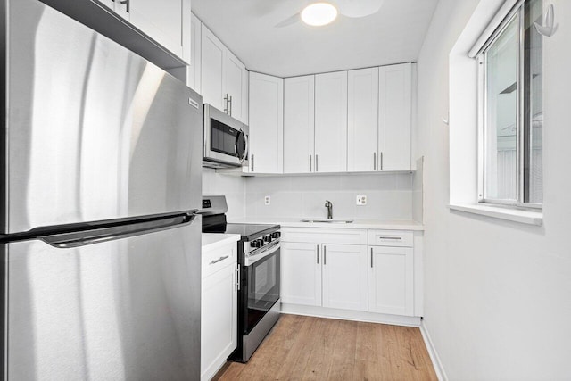 kitchen with sink, ceiling fan, light hardwood / wood-style floors, white cabinetry, and stainless steel appliances