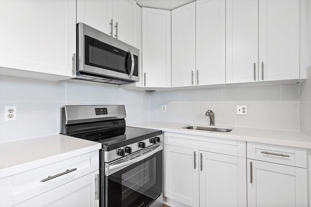 kitchen featuring white cabinets, decorative backsplash, stainless steel appliances, and sink