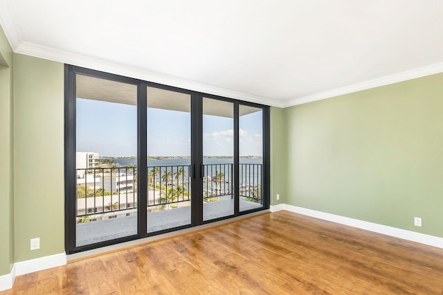 spare room with hardwood / wood-style floors, a healthy amount of sunlight, a water view, and ornamental molding