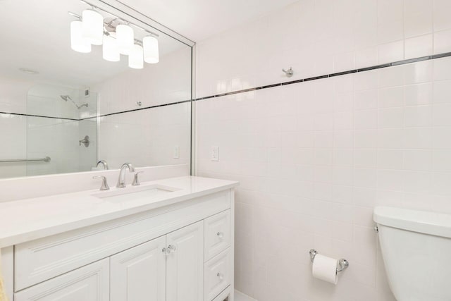 bathroom with tiled shower, vanity, tile walls, and toilet