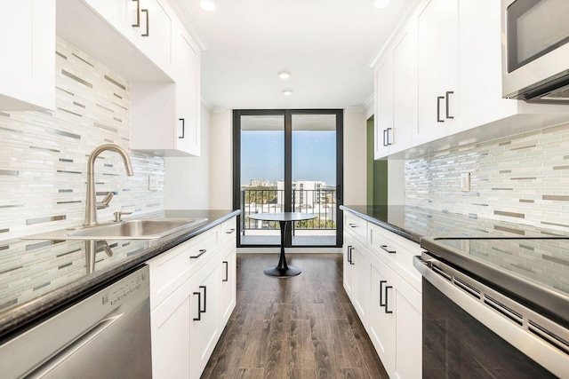 kitchen with expansive windows, sink, white cabinets, and stainless steel appliances