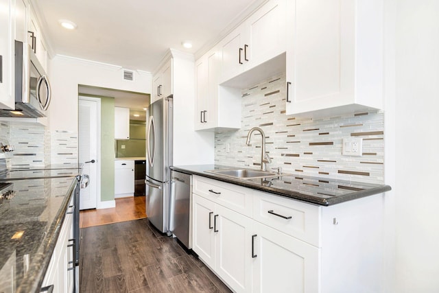 kitchen with dark wood-type flooring, dark stone counters, sink, white cabinetry, and stainless steel appliances