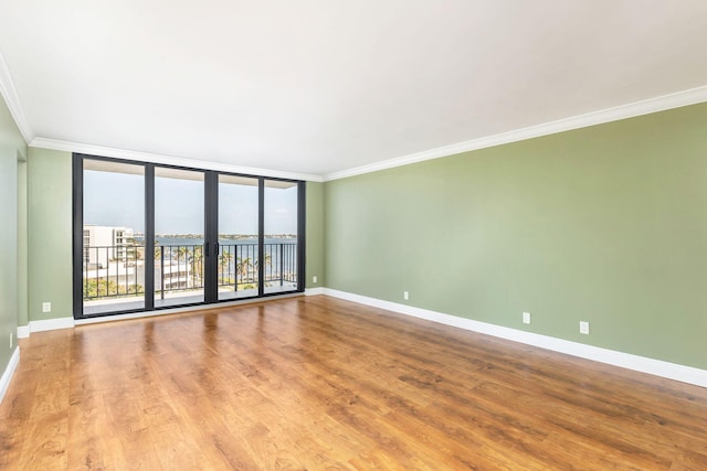 unfurnished room with crown molding, hardwood / wood-style floors, and expansive windows