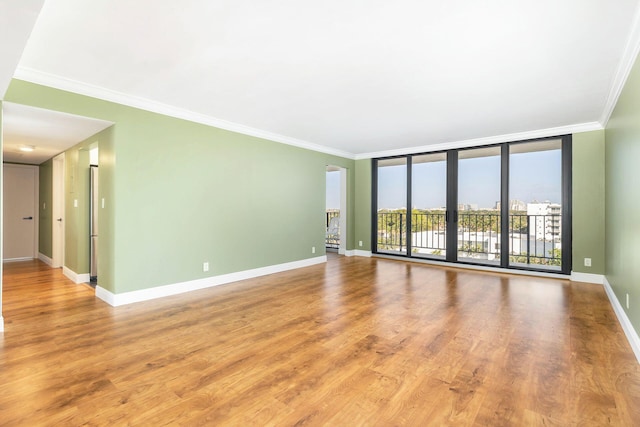 unfurnished room with hardwood / wood-style floors, a wall of windows, and ornamental molding