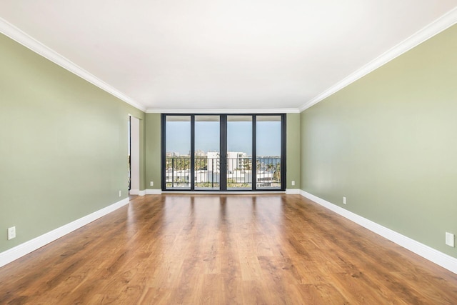 empty room featuring hardwood / wood-style floors, expansive windows, and crown molding