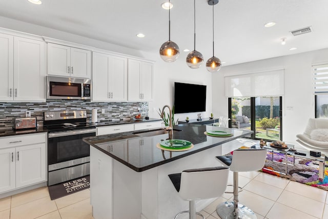 kitchen with white cabinets, sink, stainless steel appliances, and a kitchen island with sink