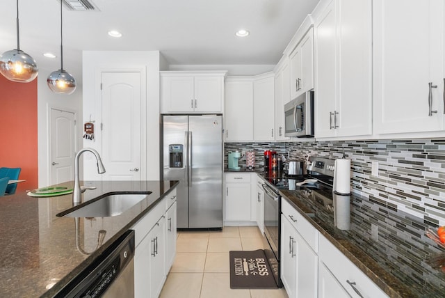 kitchen with sink, stainless steel appliances, white cabinets, decorative light fixtures, and dark stone counters