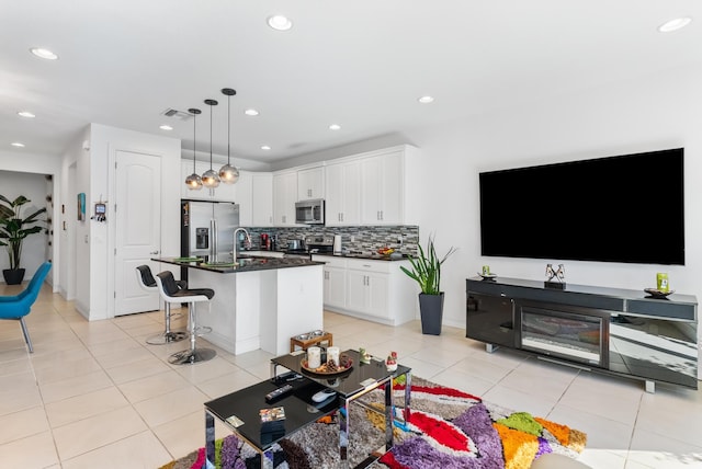 kitchen featuring white cabinetry, stainless steel appliances, a breakfast bar, and a kitchen island with sink