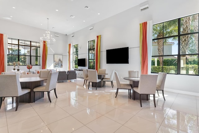 dining room with an inviting chandelier, light tile patterned floors, and a towering ceiling